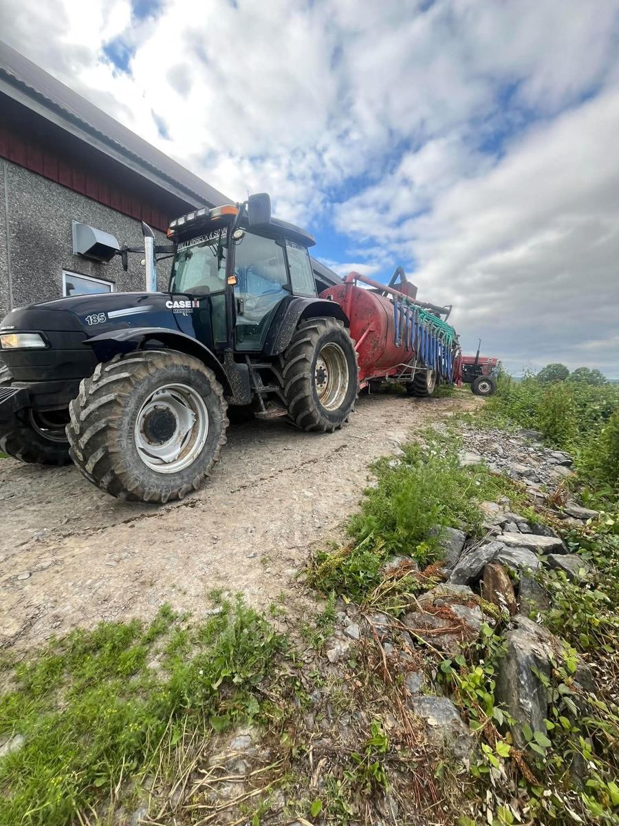 Case IH-traktor med gjødselvogn ved låve